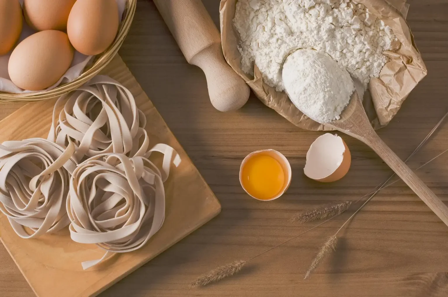 Fresh egg tagliatelle with eggs and flour on a wooden board