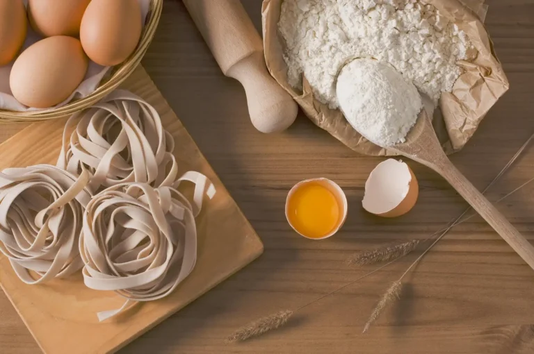 Fresh egg tagliatelle with eggs and flour on a wooden board