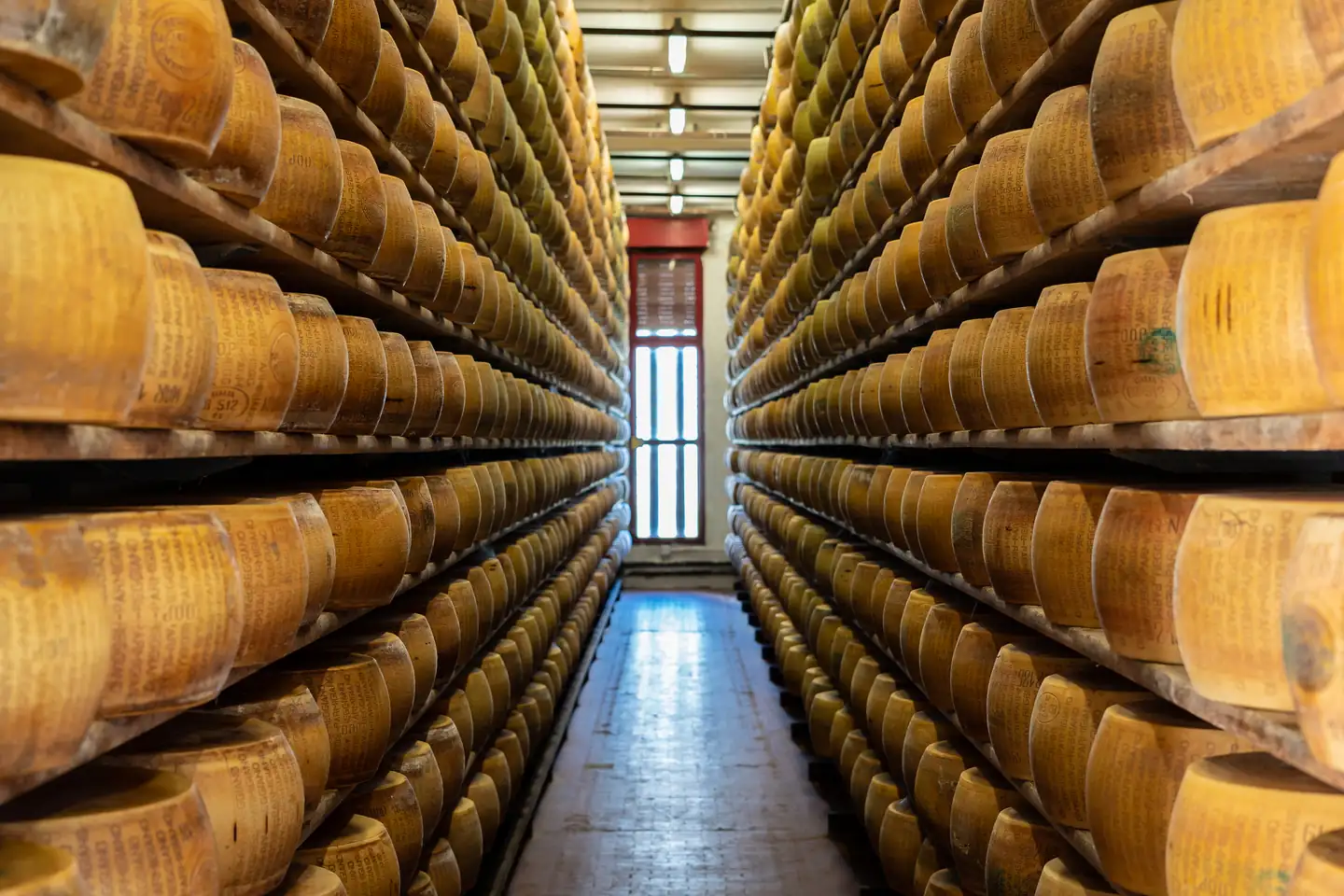 Aisle of Parmigiano Reggiano wheels ageing in an Emilia-Romagna warehouse